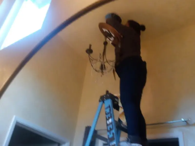 Electrician installing a chandelier in a Waverly residence